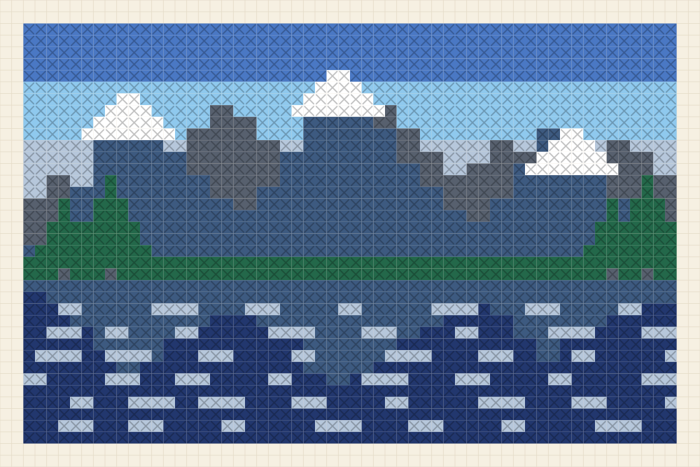 Wide cross stitch chart of a snow capped mountain range above a still lake that carries the near ridge as a reflection